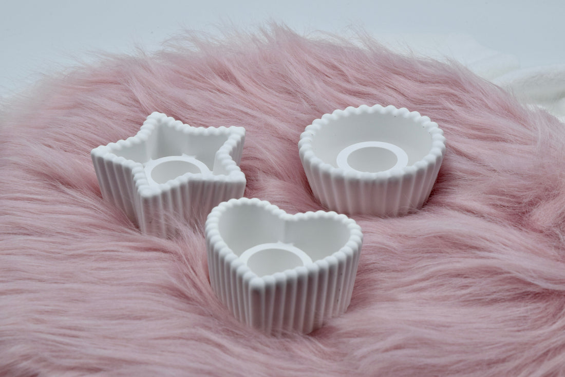 Drei handgemachte weiße Kerzenhalter aus Gießpulver auf einem rosa Fell